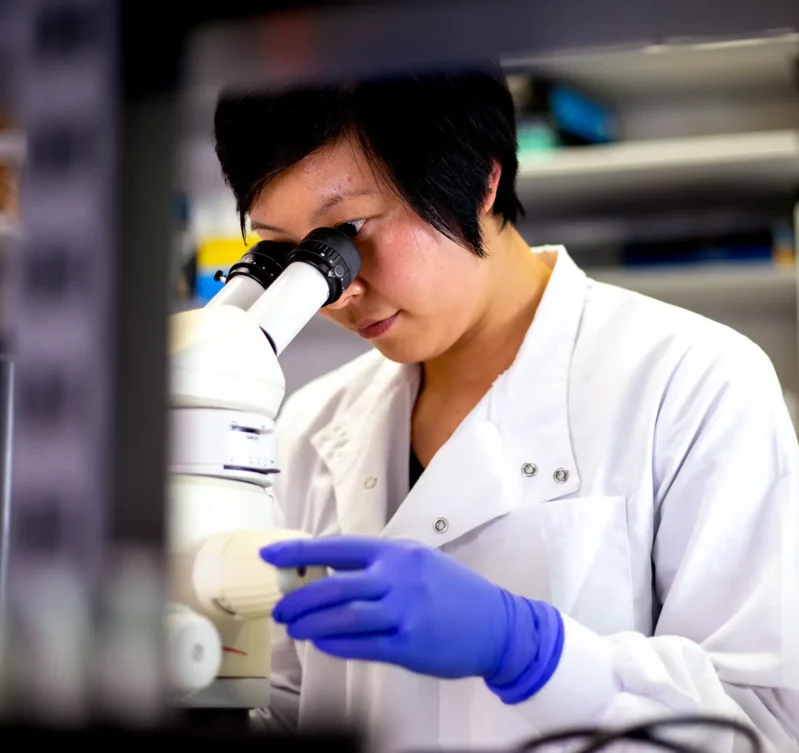 A female lab technician looking through a microscope